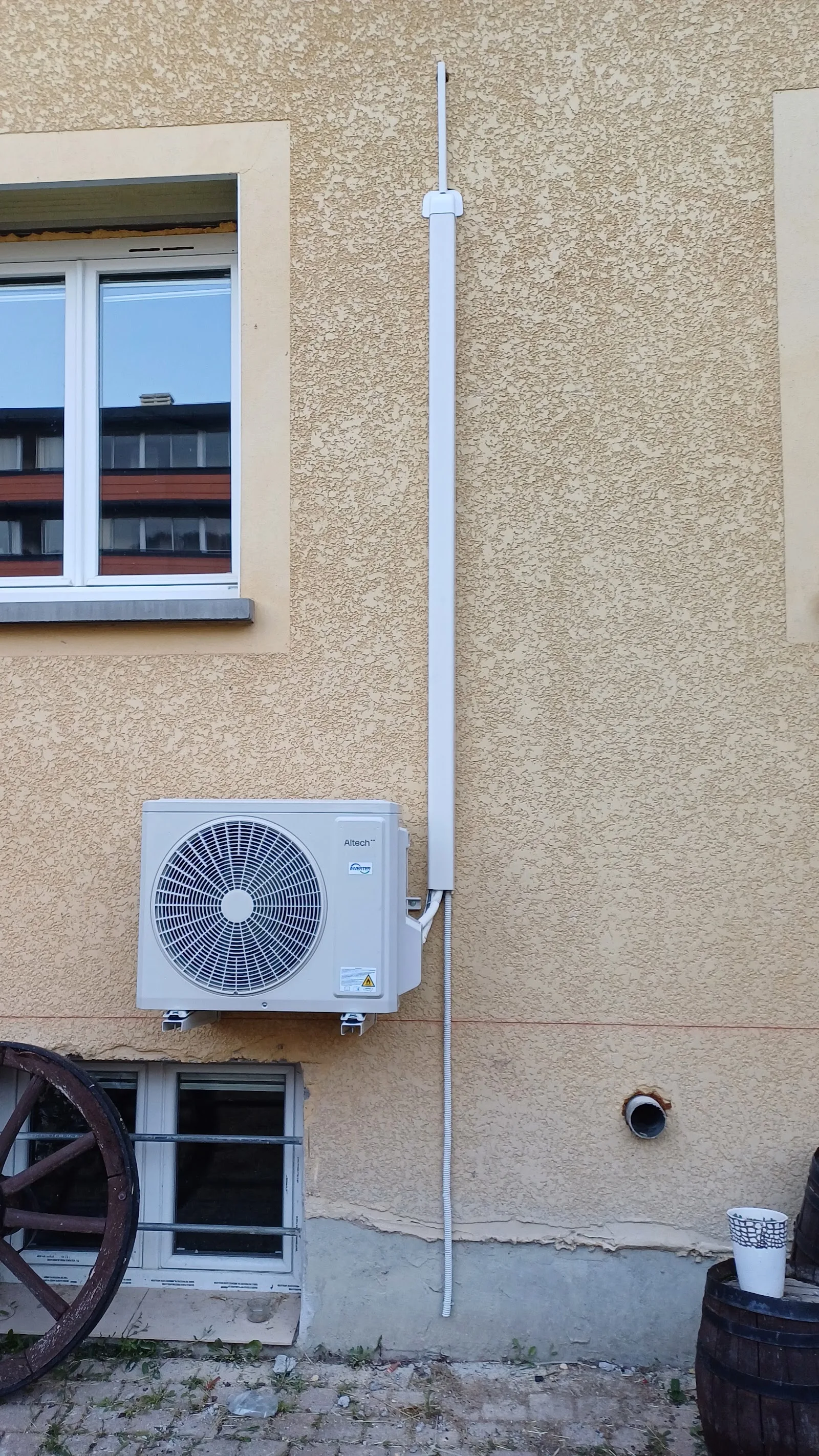 Unité extérieure de climatisation posée sur une façade crépie, liaison frigorifique gainée et alignée